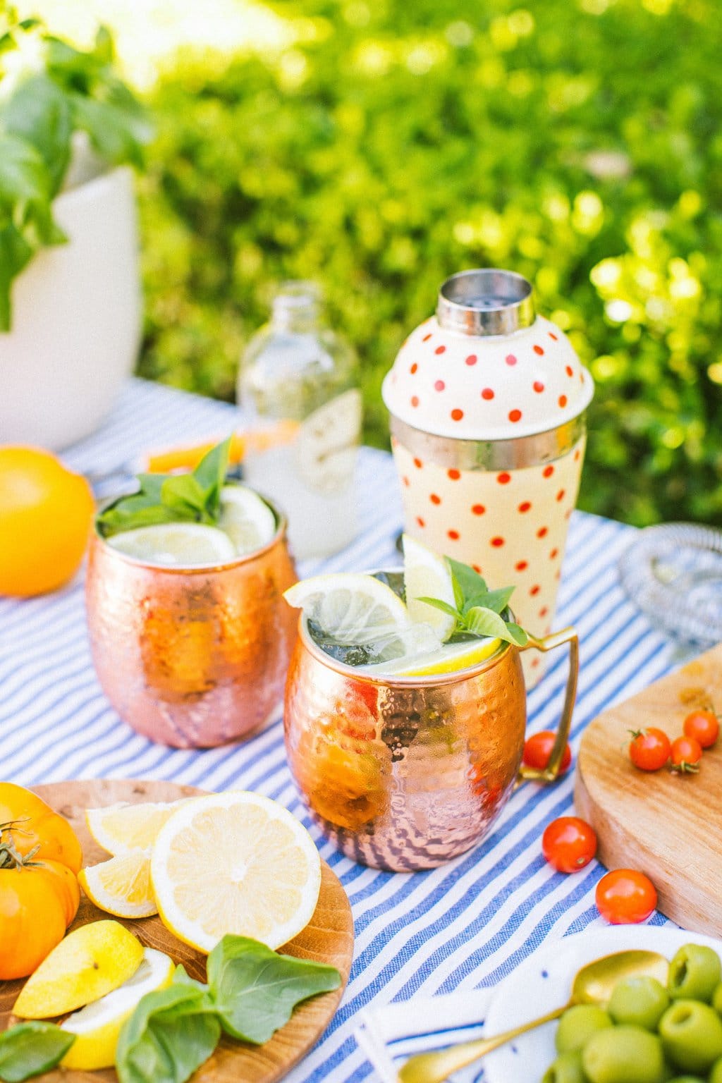 two copper mugs full of limoncello mules beside a cocktail shaker