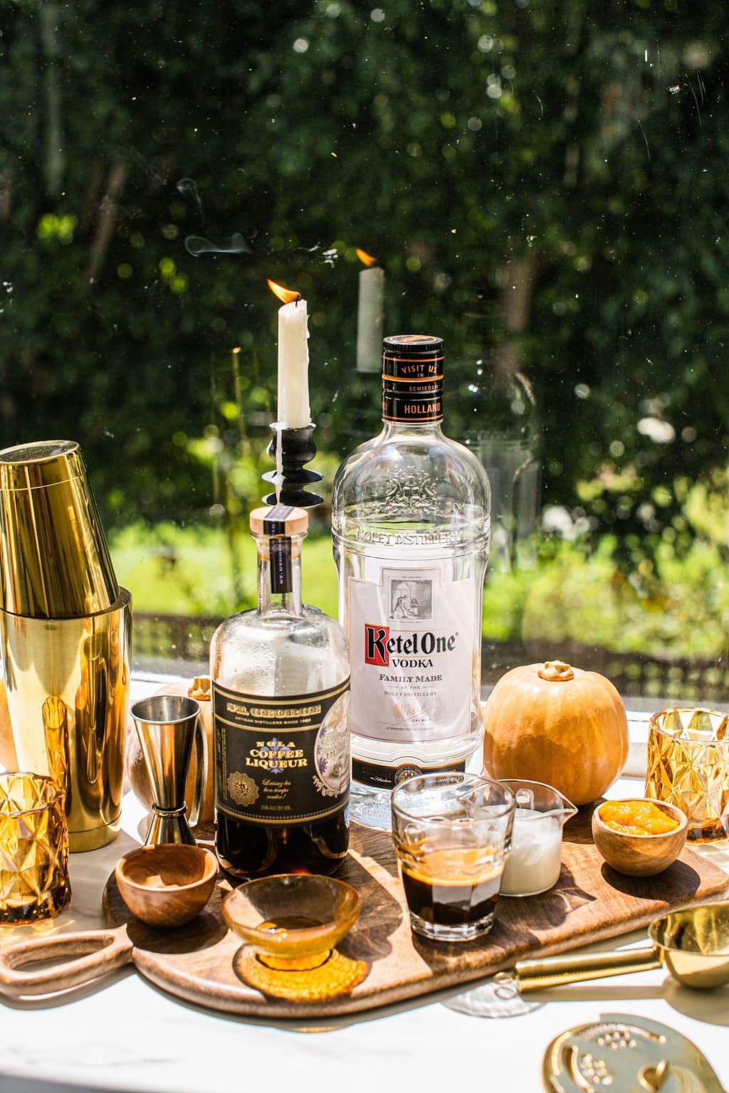 bottles of ketel one, coffee liqueur, espresso, pumpkin puree, pumpkin creamer, maple syrup, and supplies like the cocktail shaker