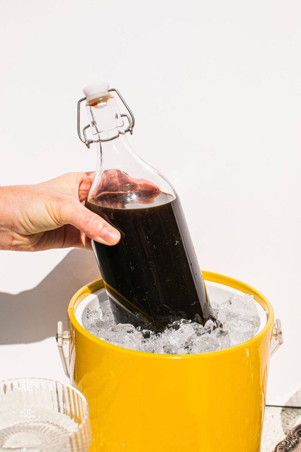 a bottle of espresso martini mix in a bucket of ice and a hand holding the bottle