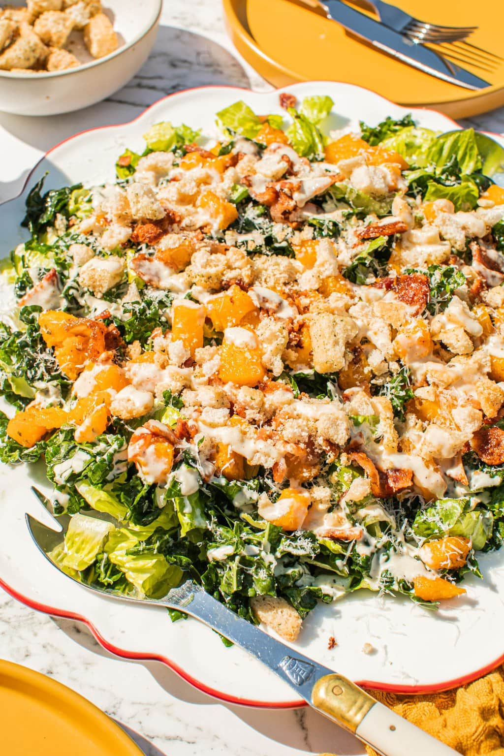 a close up shot of the fall kale caesar salad topped with homemade dressing and crumbled croutons