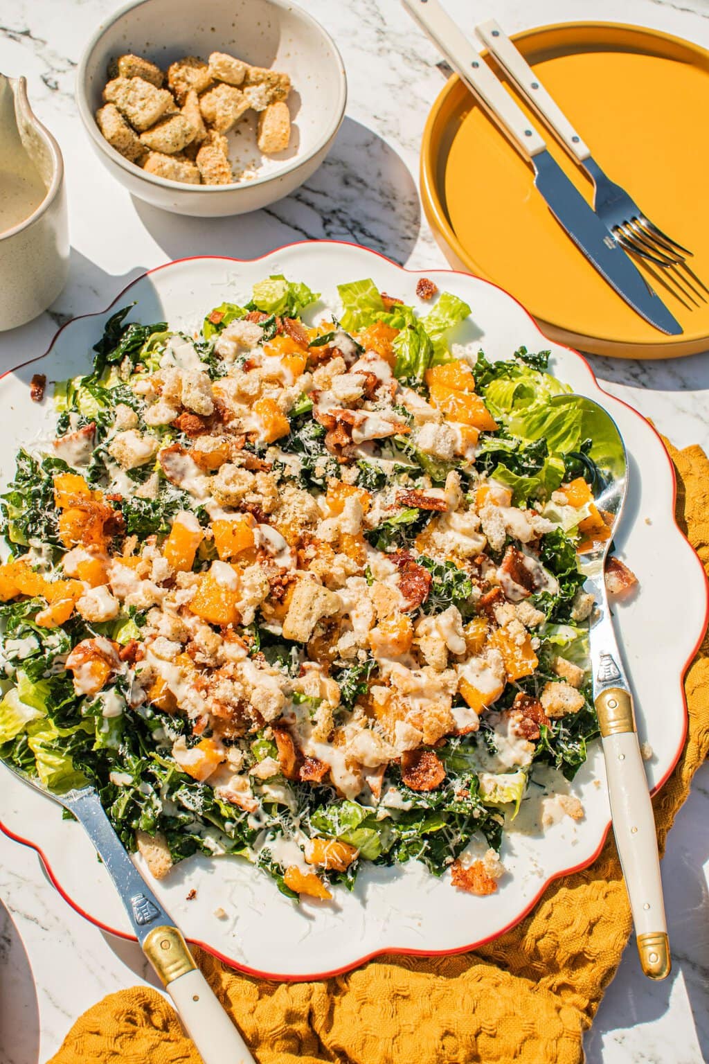 a large serving of autumn kale caesar with utensils on it 