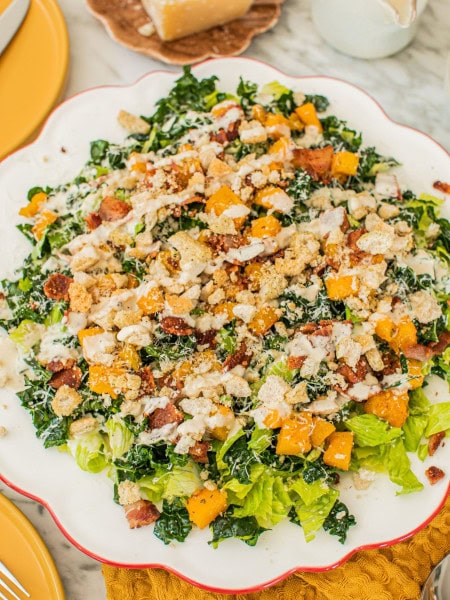 a large serving platter of kale caesar salad drizzled in homemade dressing