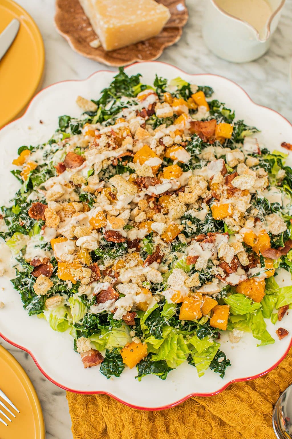 a large serving platter of kale caesar salad drizzled in homemade dressing