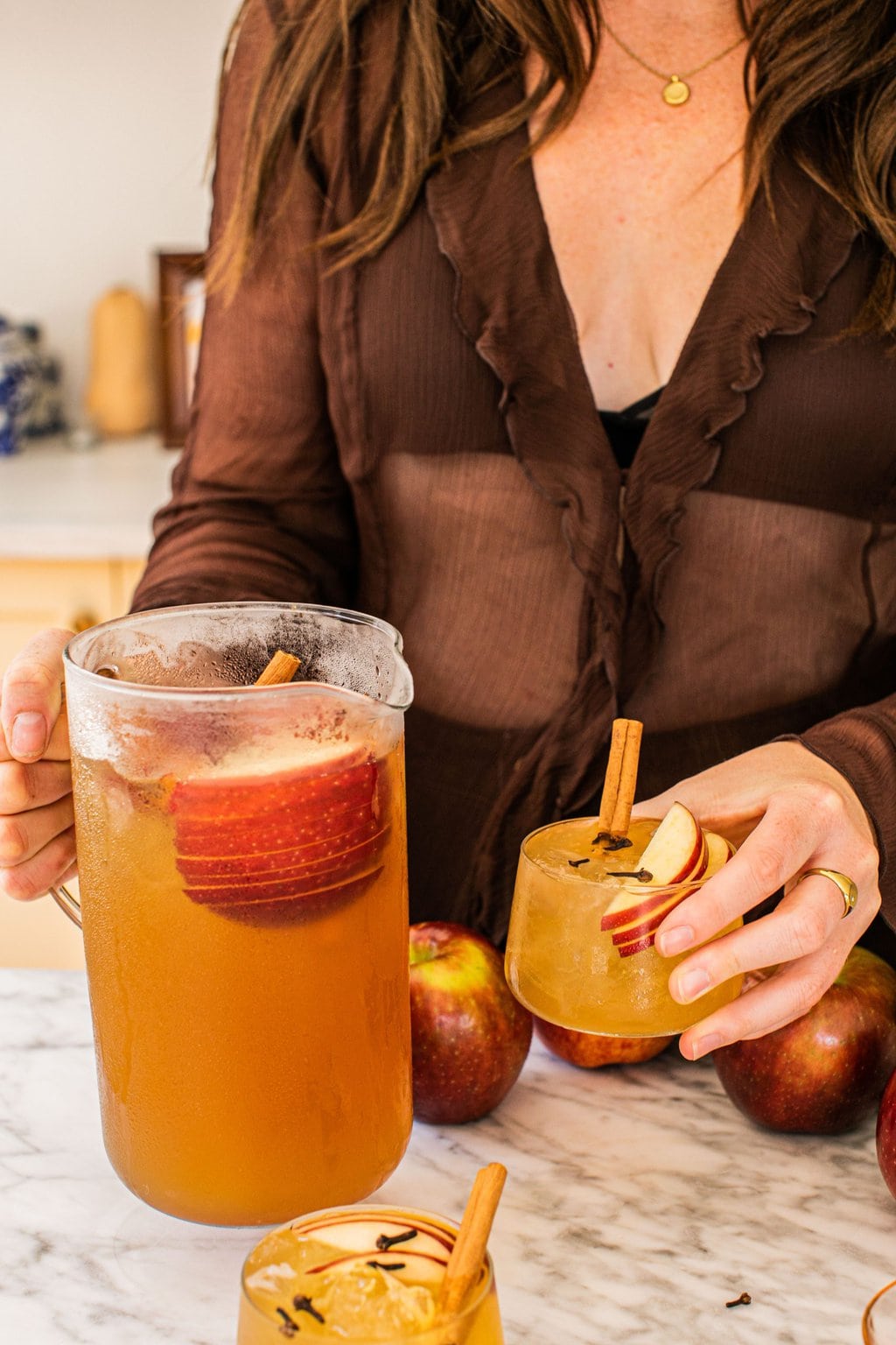 elizabeth holding the pitcher of bourbon apple cider and an individual serving in the other hand