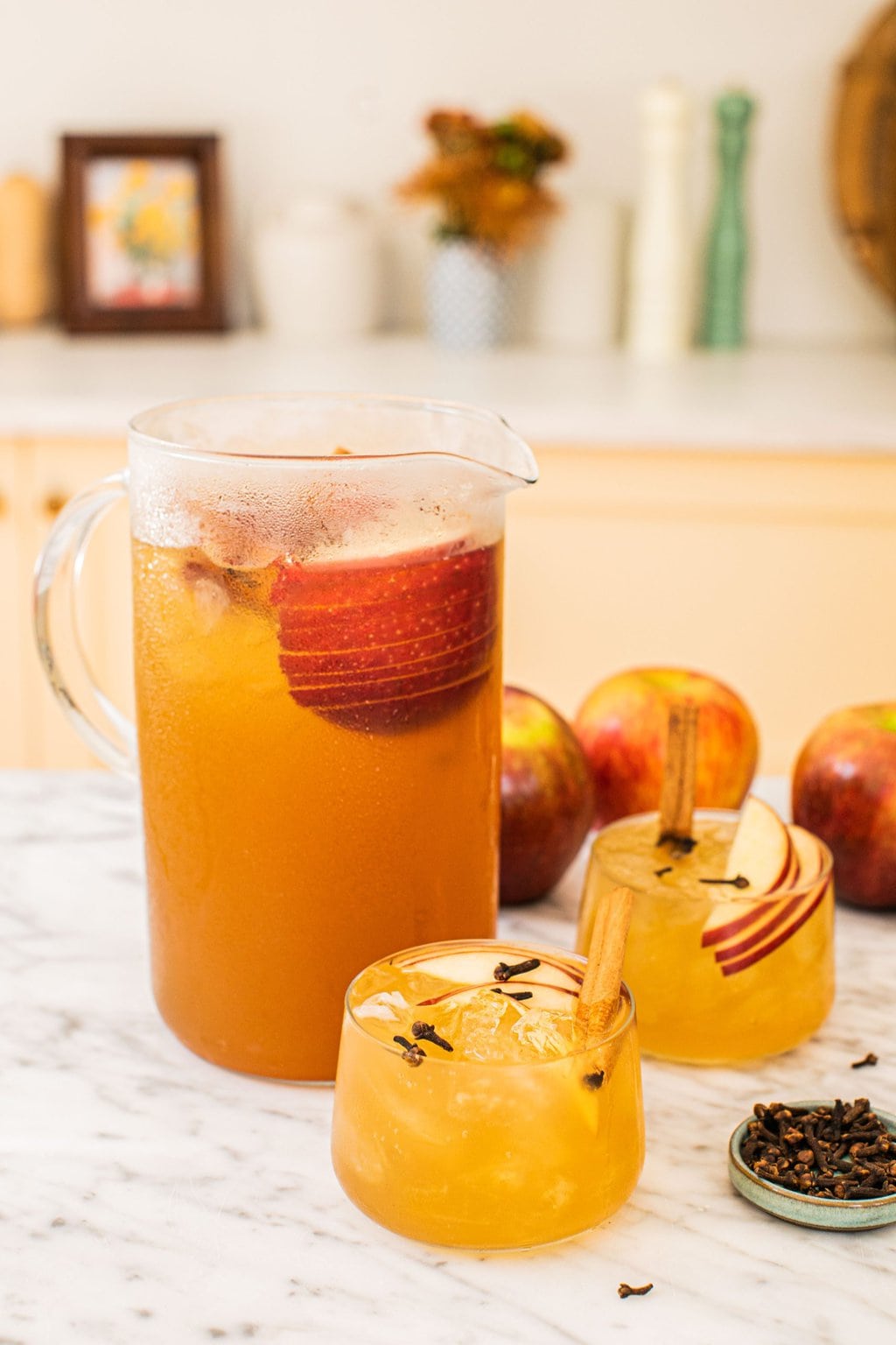 a big pitcher of bourbon apple cider with two glasses of the cocktail in front