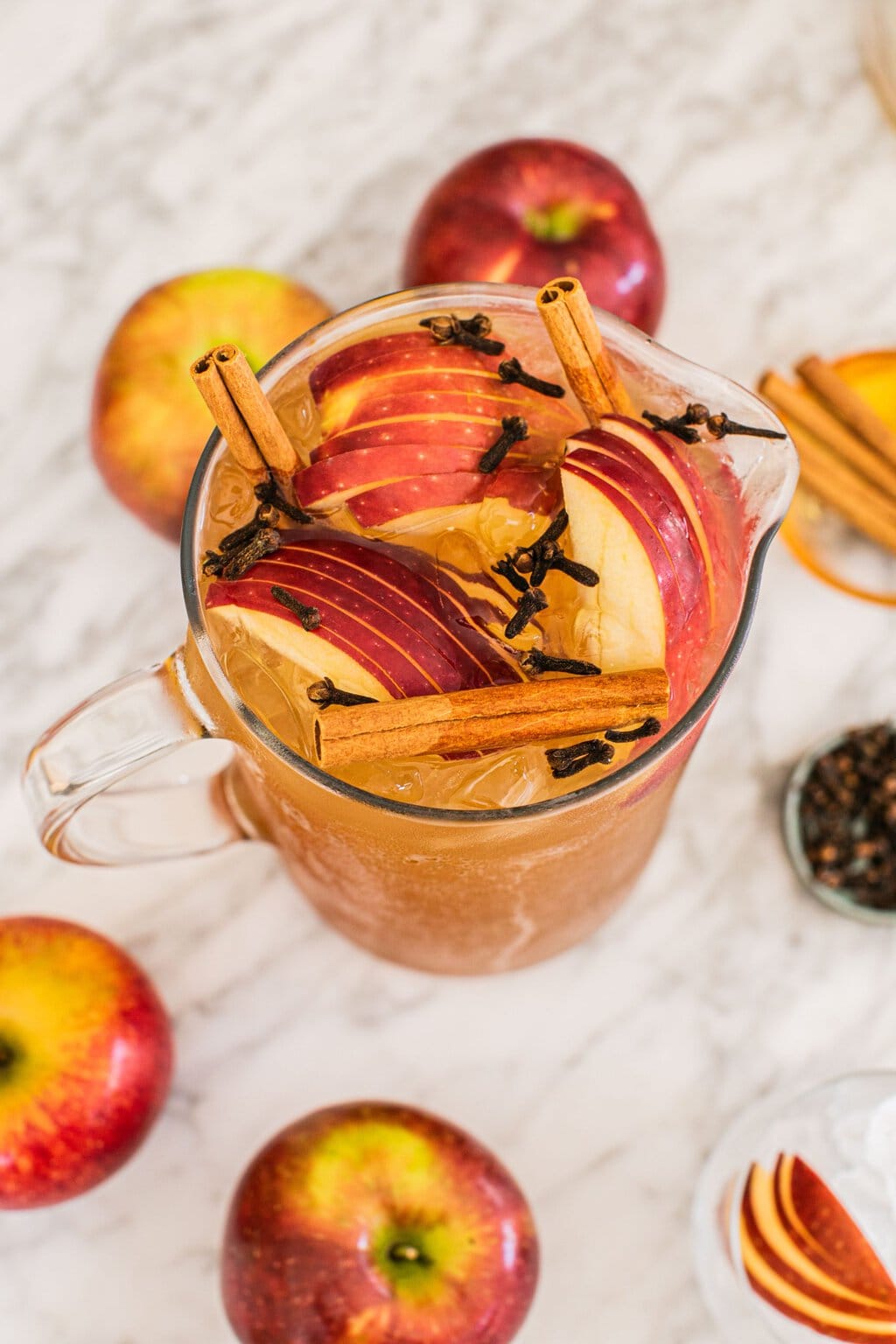 a large pitcher of bourbon apple cider with cinnamon sticks, apples, and star anise garnishing the top