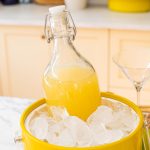 a large carafe of pear martini chilling in a yellow ice bucket