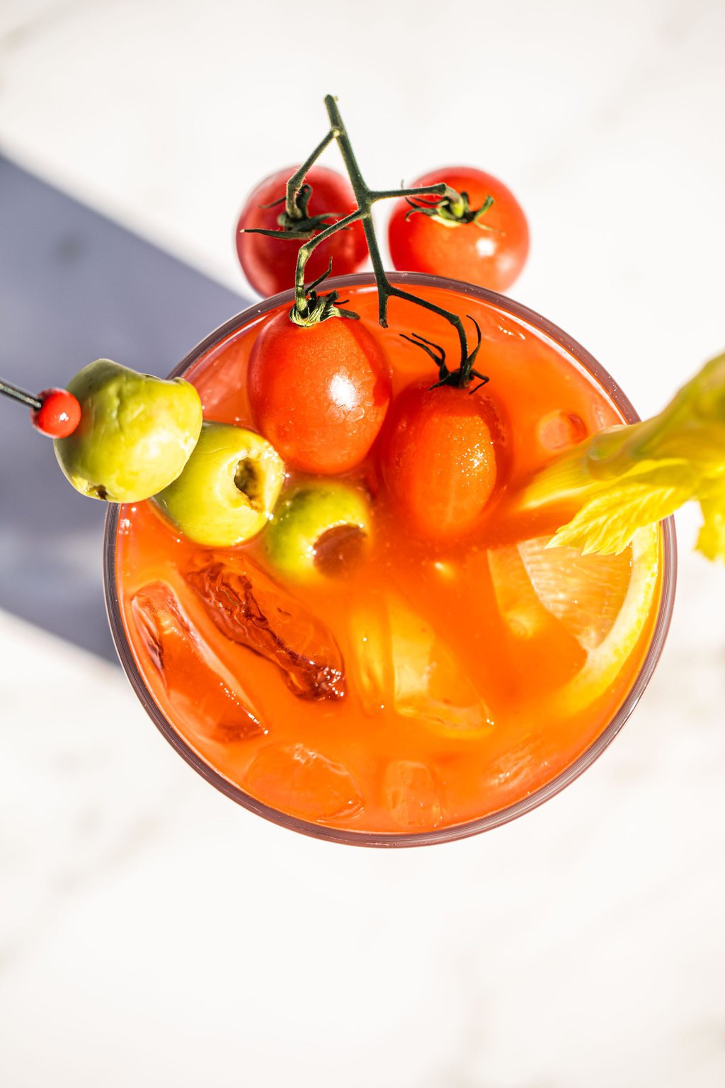 an overhead shot of a bloody mary garnished with olives, tomatoes, and celery 