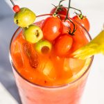 a glass of bloody mary with olives, tomatoes, and celery as garnish