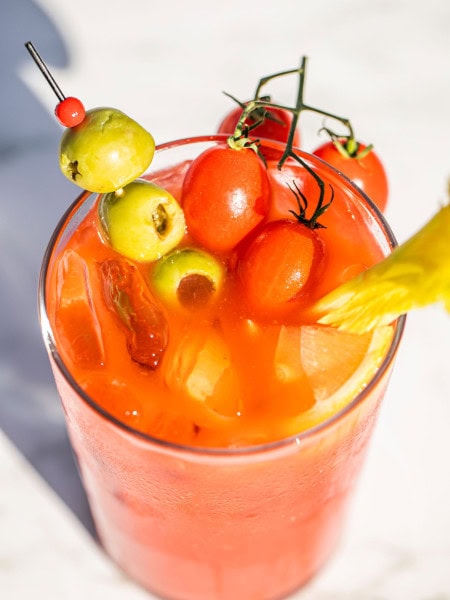 a glass of bloody mary with olives, tomatoes, and celery as garnish