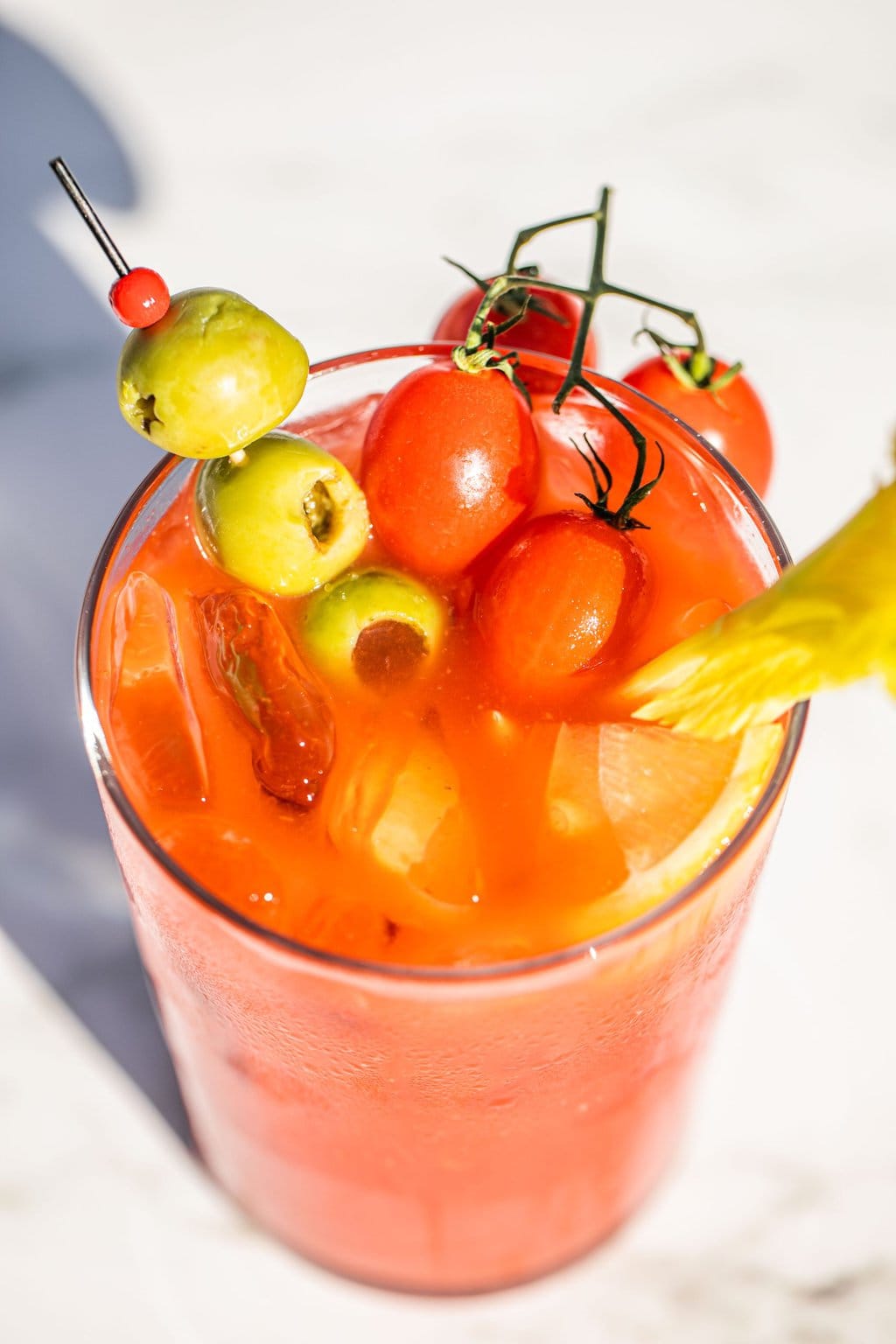 a glass of bloody mary with olives, tomatoes, and celery as garnish