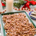 peppermint bark puppy chow on a baking sheet with christmas decor and a candle around it