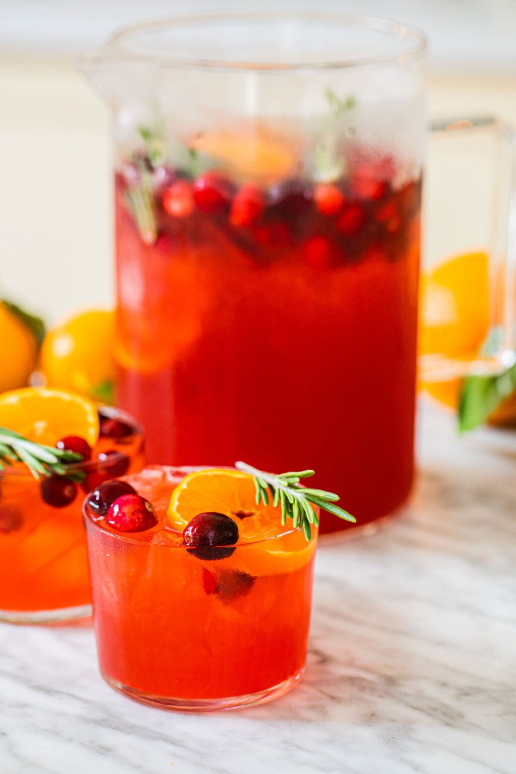 a large pitcher with cranberry gin cocktail and smaller glasses 