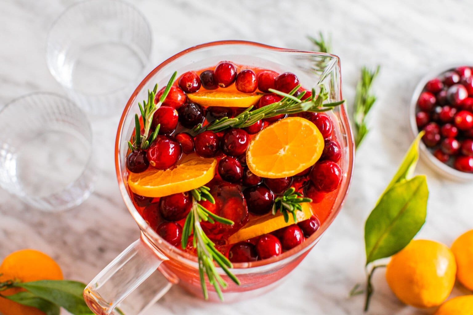  a pitcher with tangerine slices, fresh cranberries and rosemary sprigs 