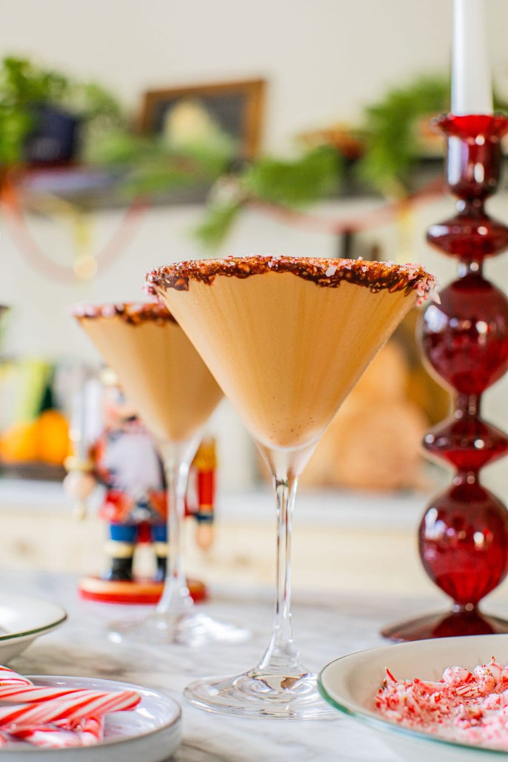 two martini glasses rimmed with chocolate syrup and crushed canes full of espresso martinis