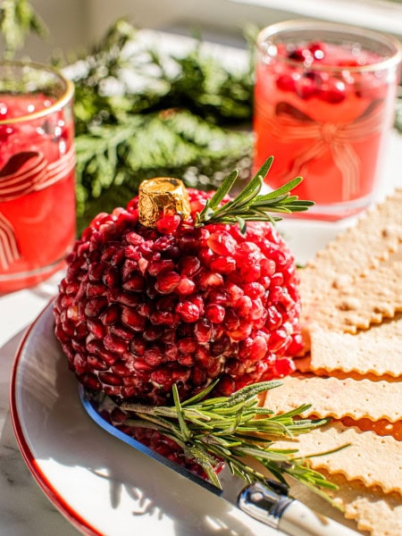 pomegranate ornament christmas cheeseball on a plate with crackers