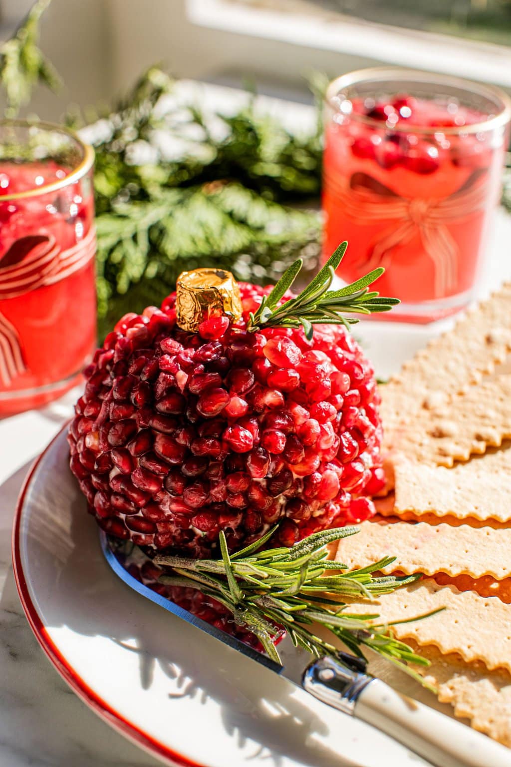 pomegranate ornament christmas cheeseball on a plate with crackers