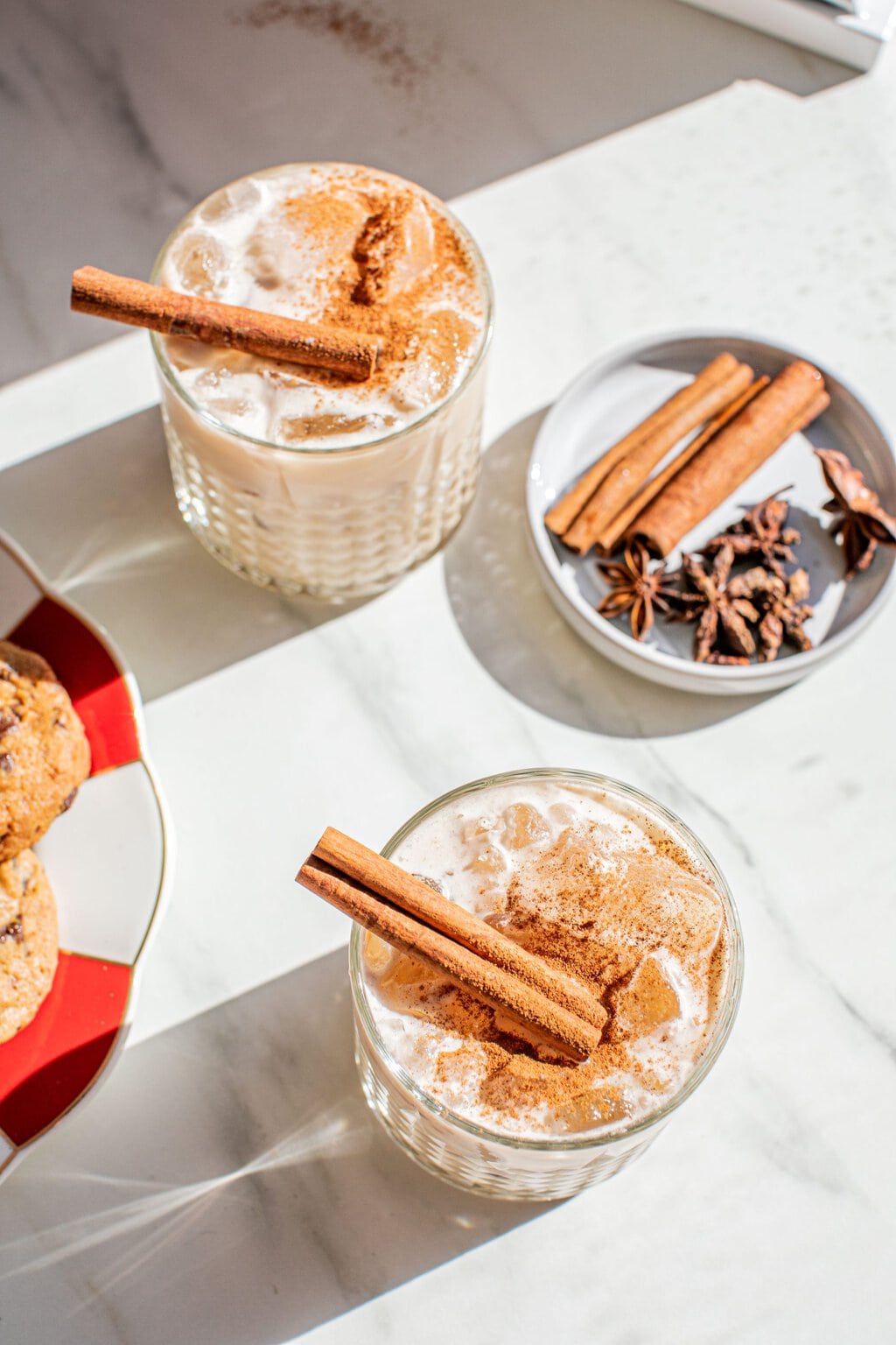 two glasses of white russian cocktails with cinnamon stick, powder, and star anise garnish