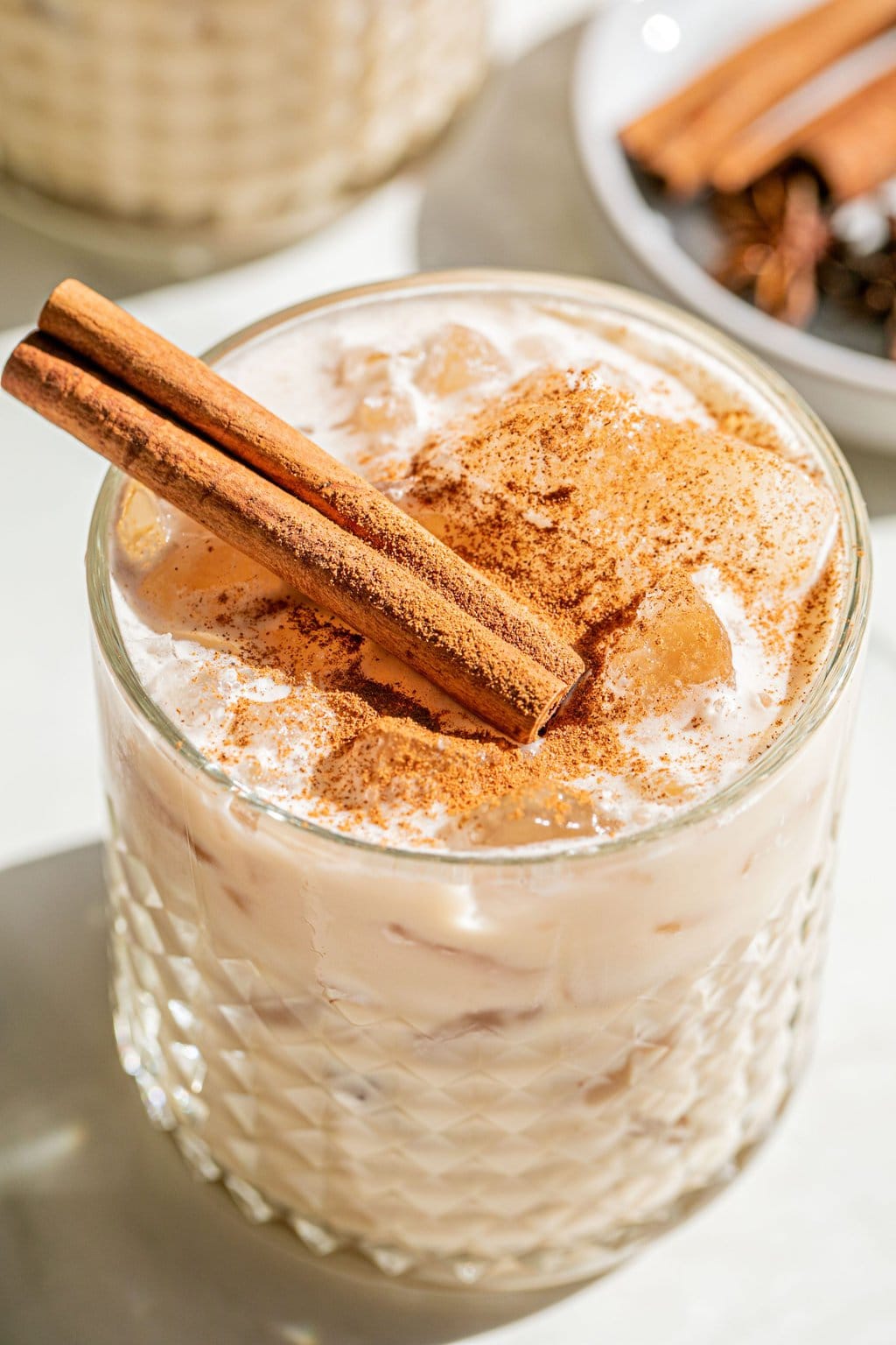 a closeup photo of a white russian with cinnamon sticks and powder on top