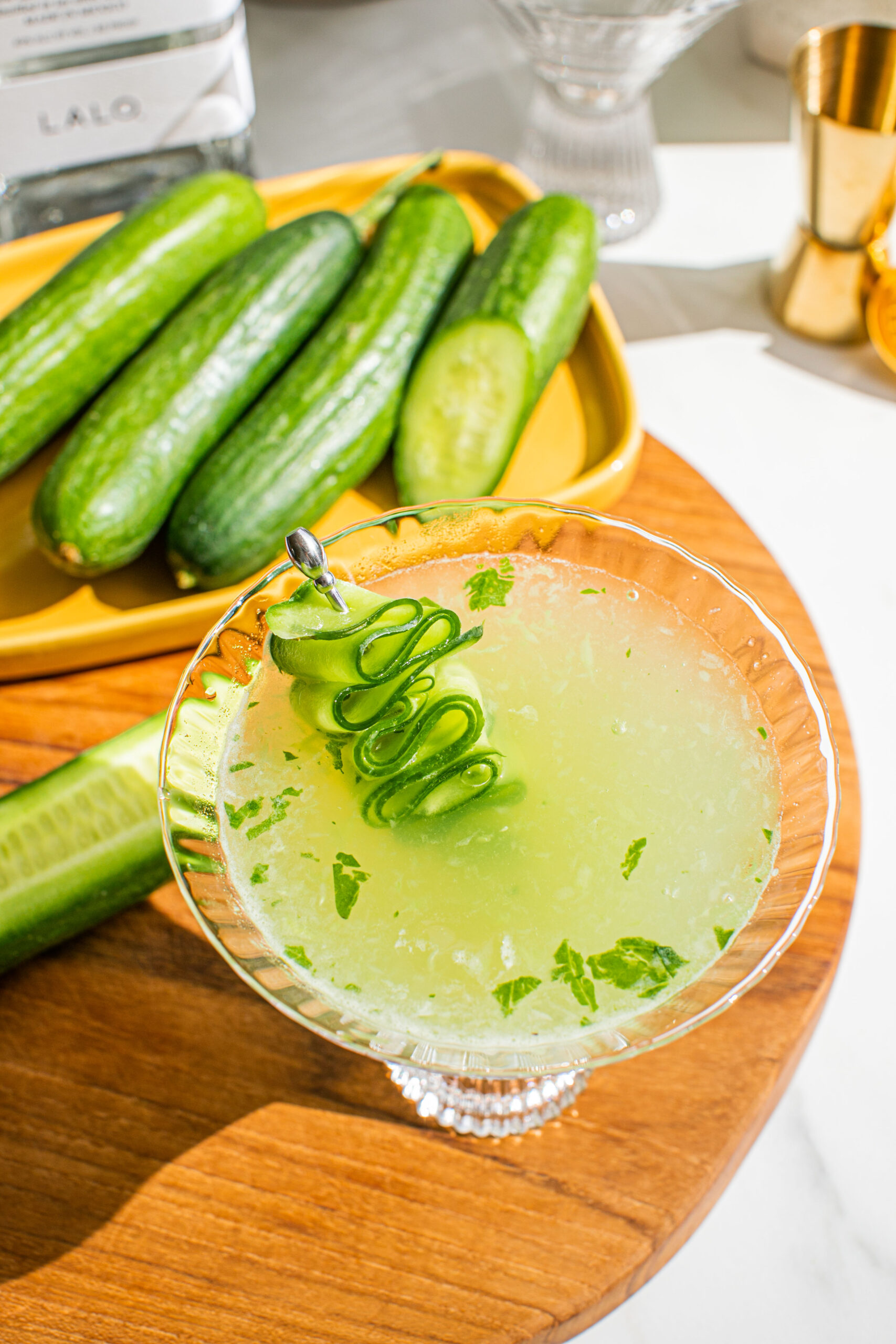 an overhead shot of cucumber spa martini with cucumbers in the background