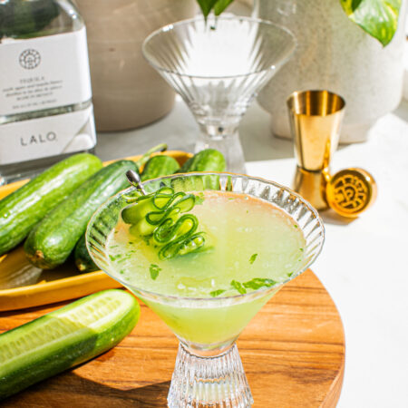 a cucumber martini on a wooden cutting board