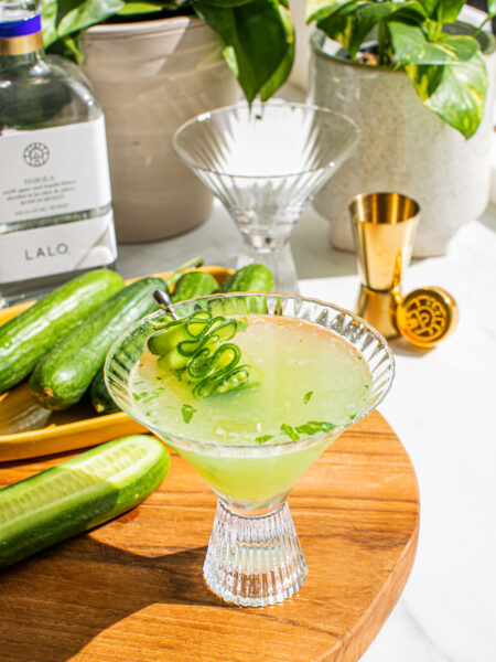 a cucumber martini on a wooden cutting board