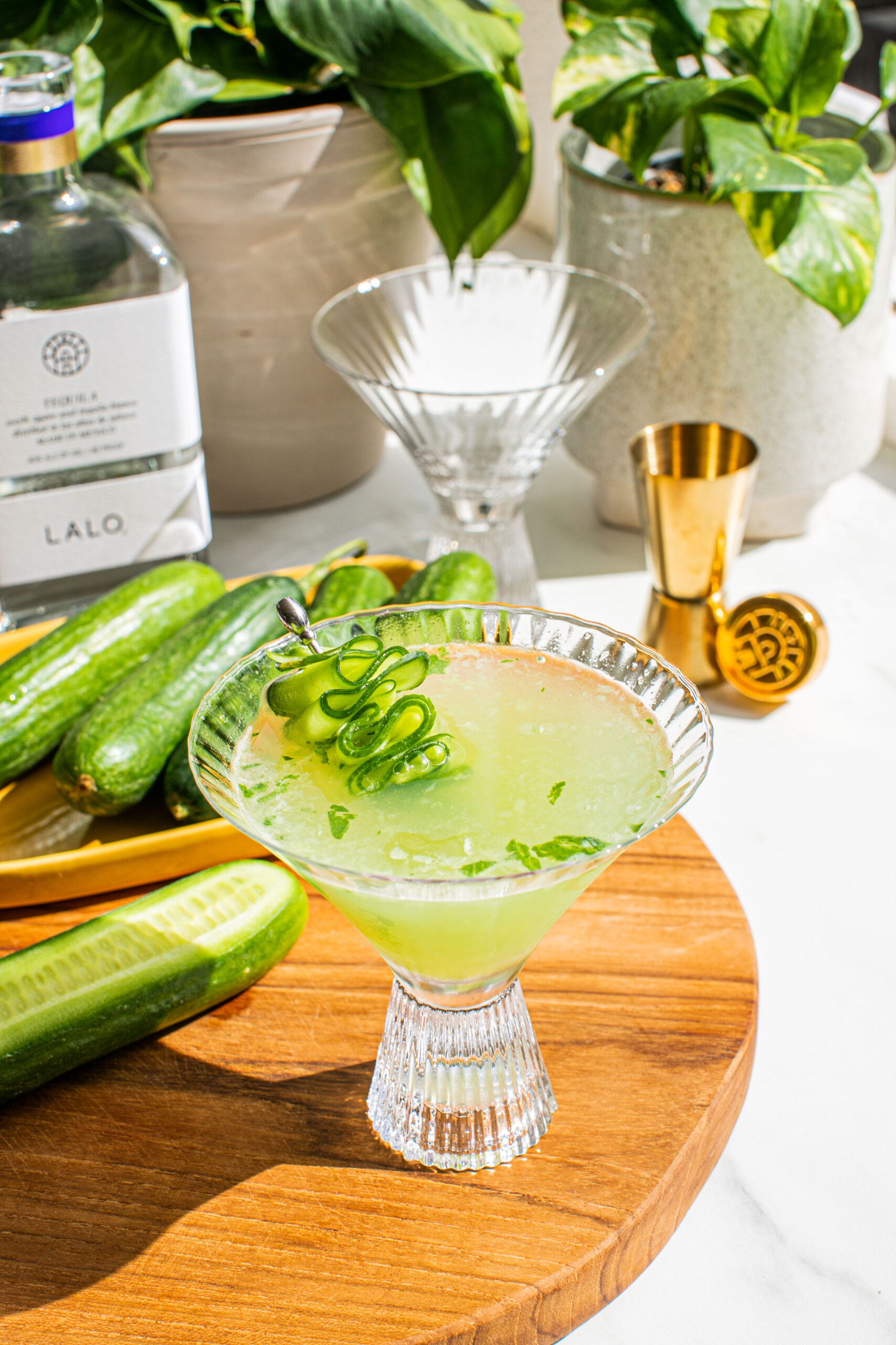 a cucumber martini on a wooden cutting board