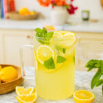 a pitcher of limoncello spritz with lemon slices around it on the counter