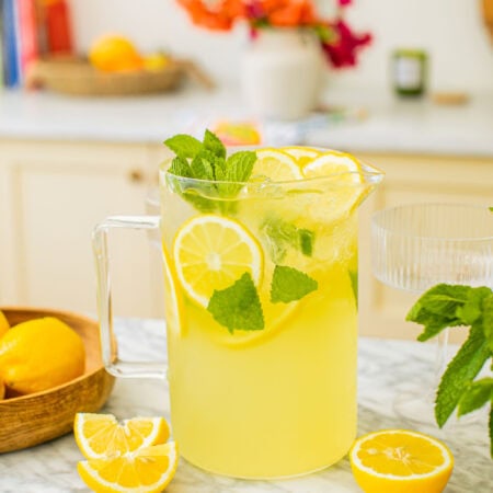 a pitcher of limoncello spritz with lemon slices around it on the counter