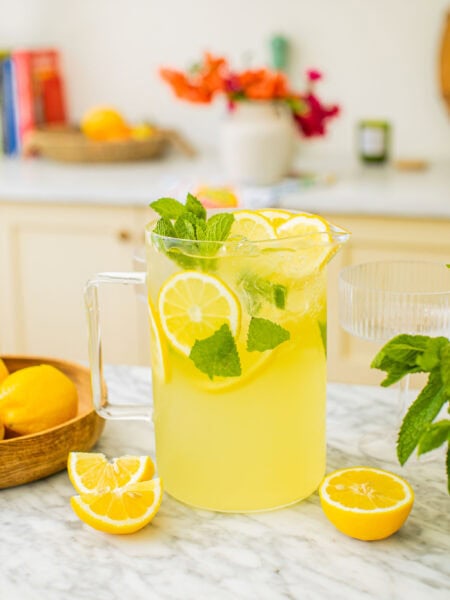a pitcher of limoncello spritz with lemon slices around it on the counter
