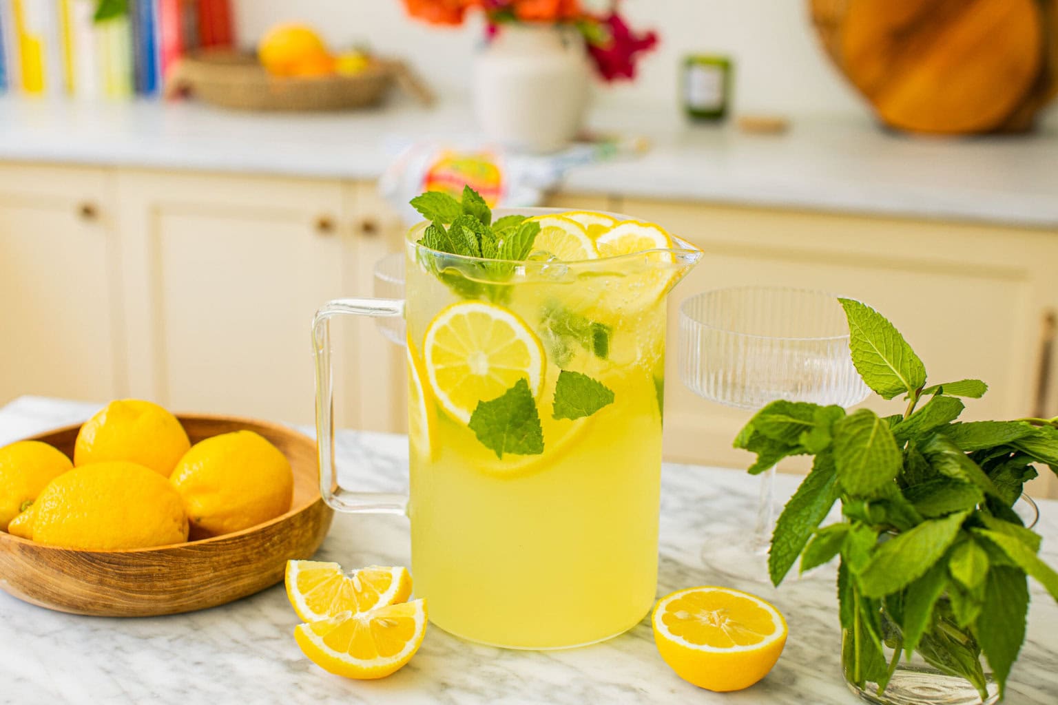 a pitcher of limoncello spritz with lemons and mint leaves around it on the counter