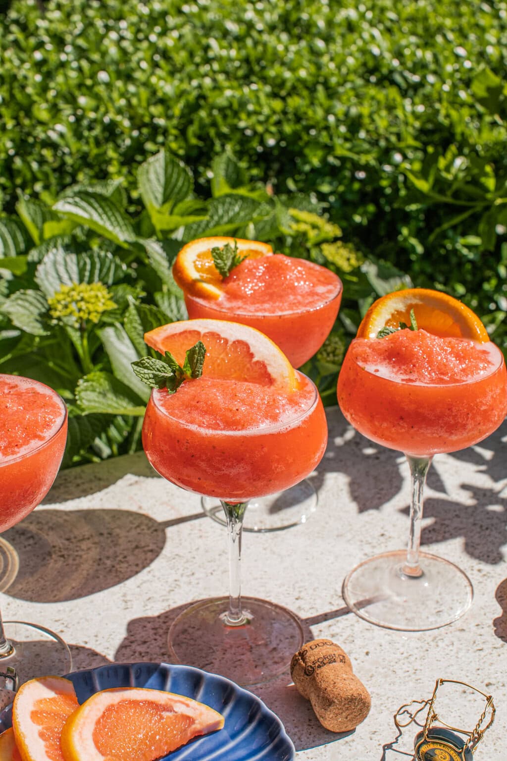 four glasses of iced aperol spritz cocktails with oranges for garnish