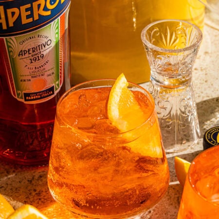 a glass full of aperol soda garnished with an orange wedge