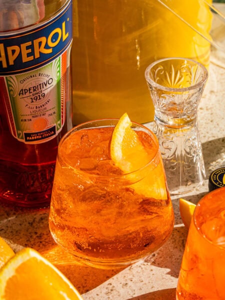 a glass full of aperol soda garnished with an orange wedge