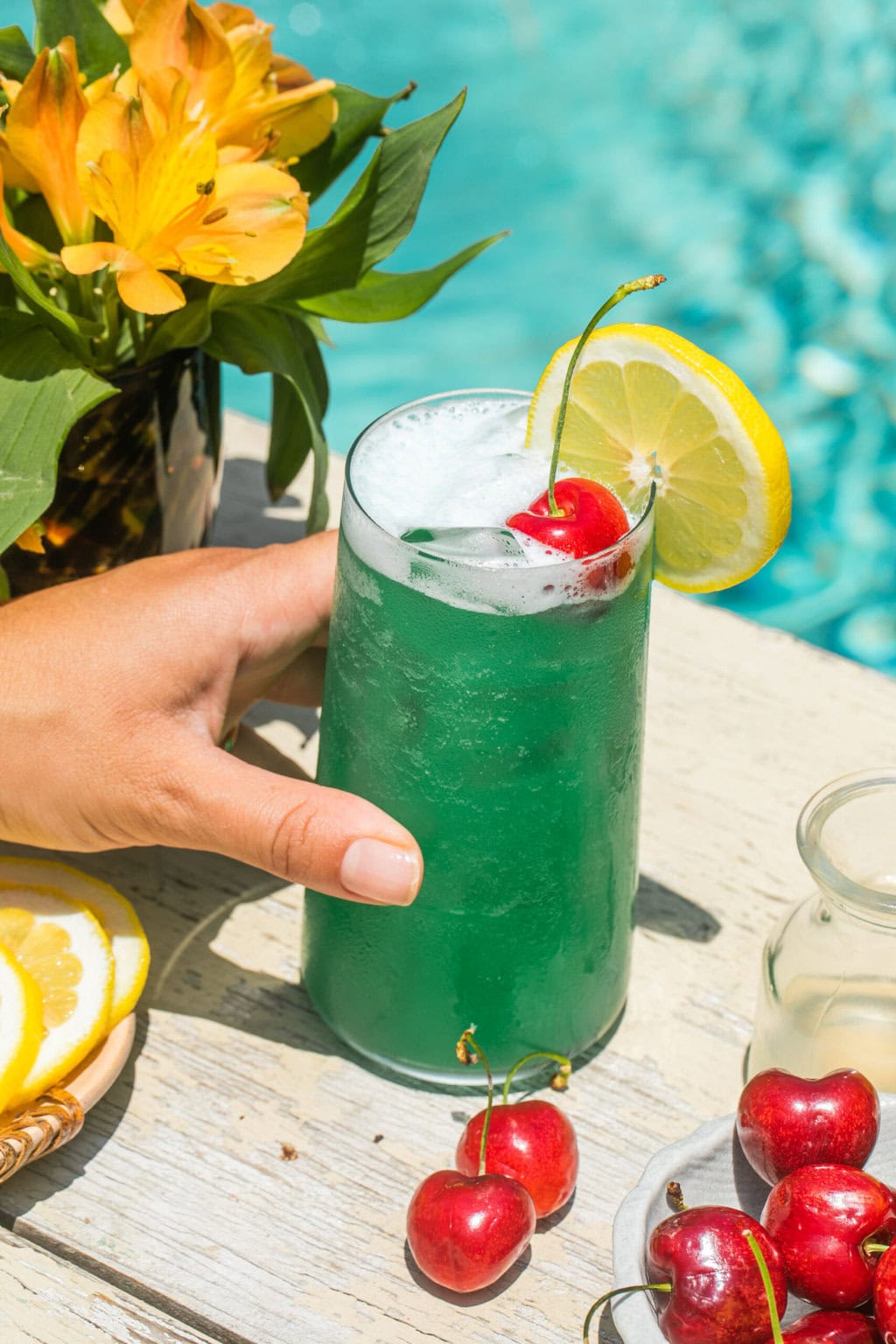 a hand holding a cup filled with a blue lagoon cocktail