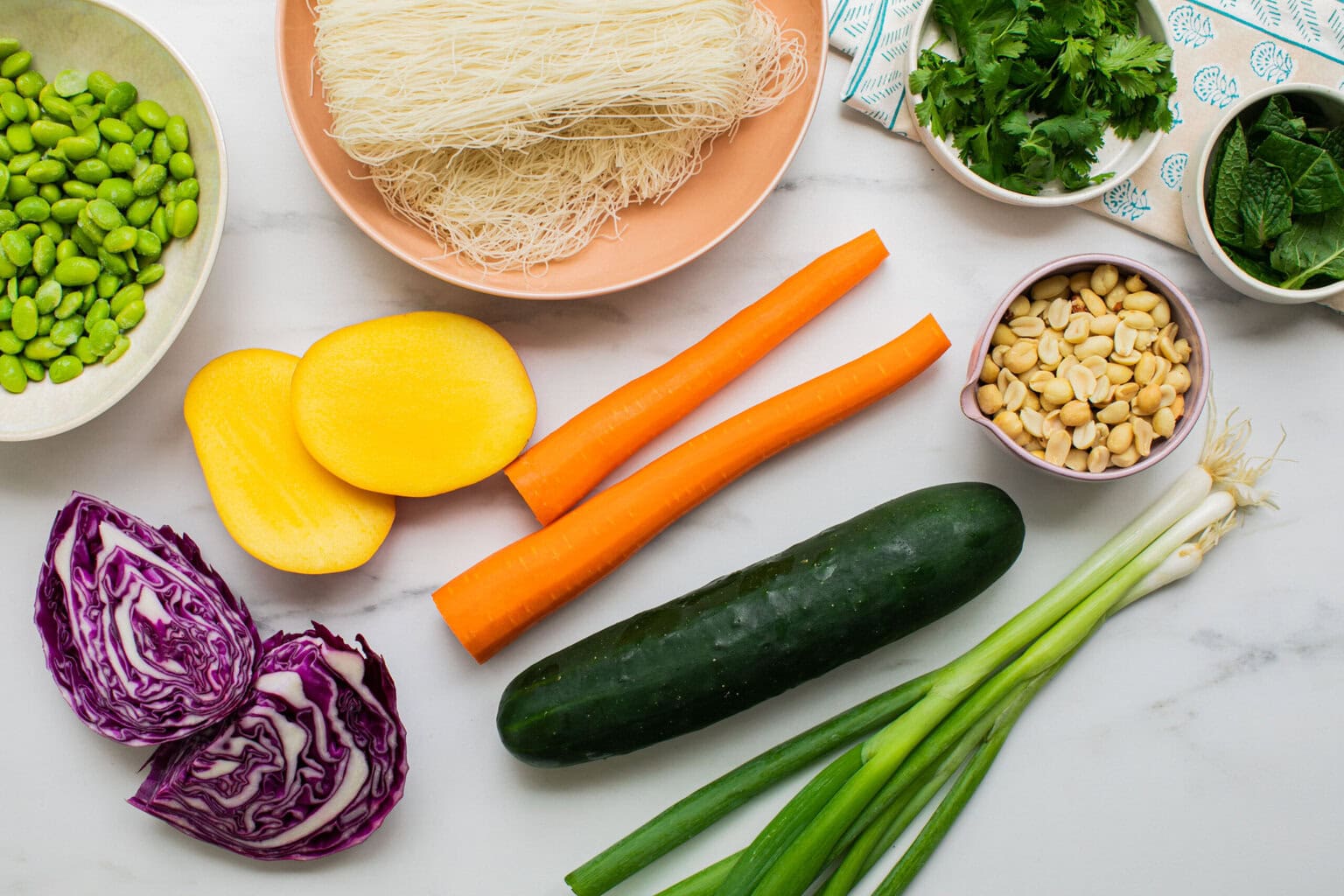 thin rice noodles, herbs, peanuts, carrots, cucumber, green onions, cabbage, mango, edamame