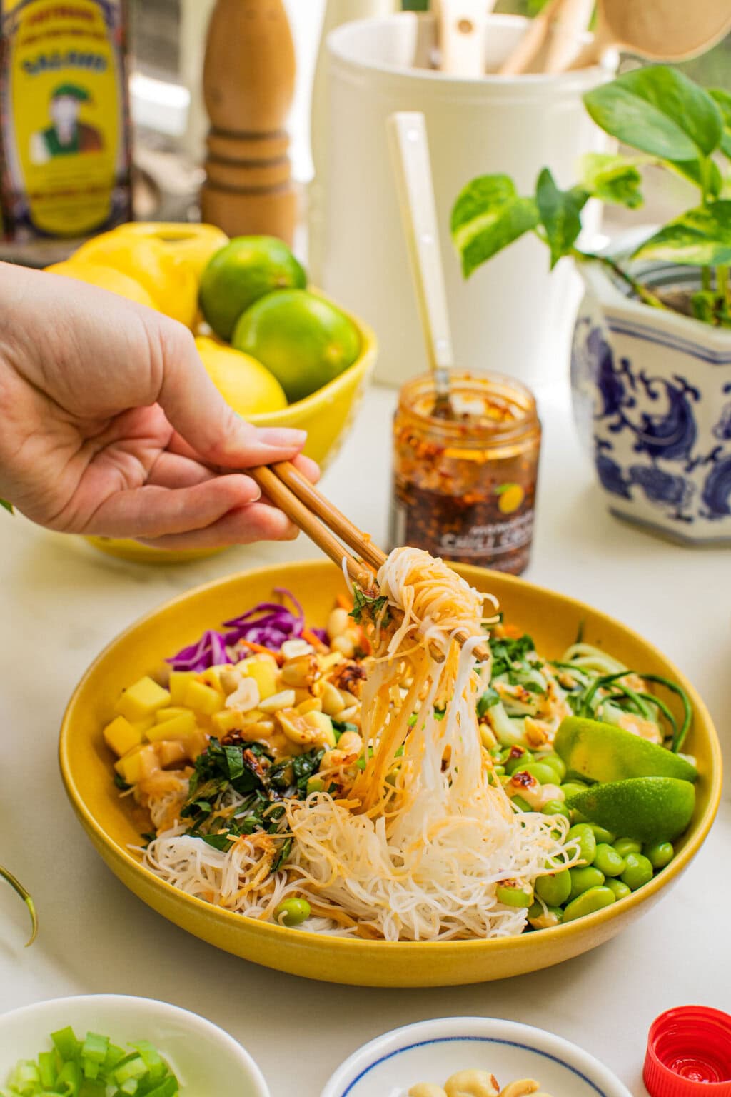 a bowl of spring roll ingredients that someone is taking a bite out of with chopsticks
