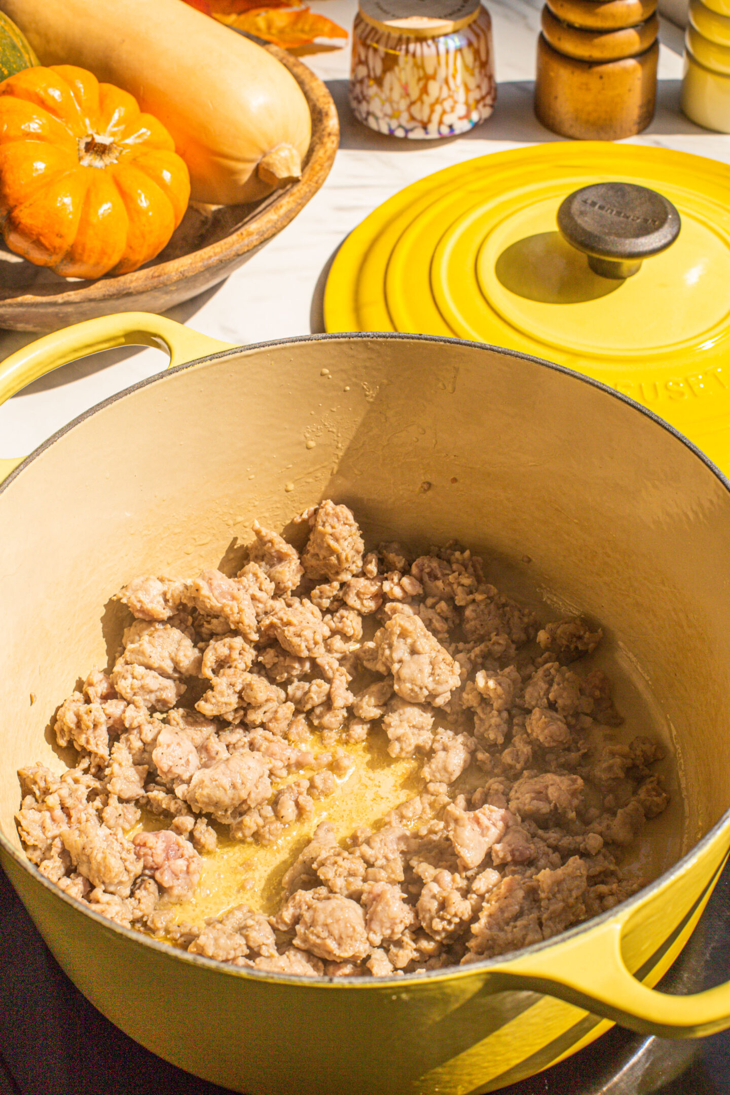 a yellow dutch oven filled with ground italian sausage cooking