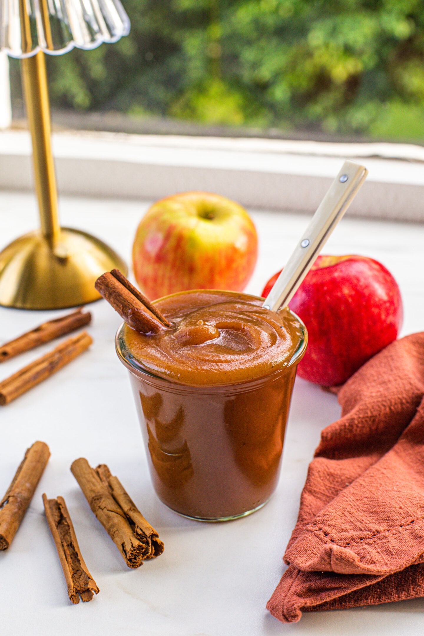 a glass jar filled with apple butter and. white spoon coming out of the jar