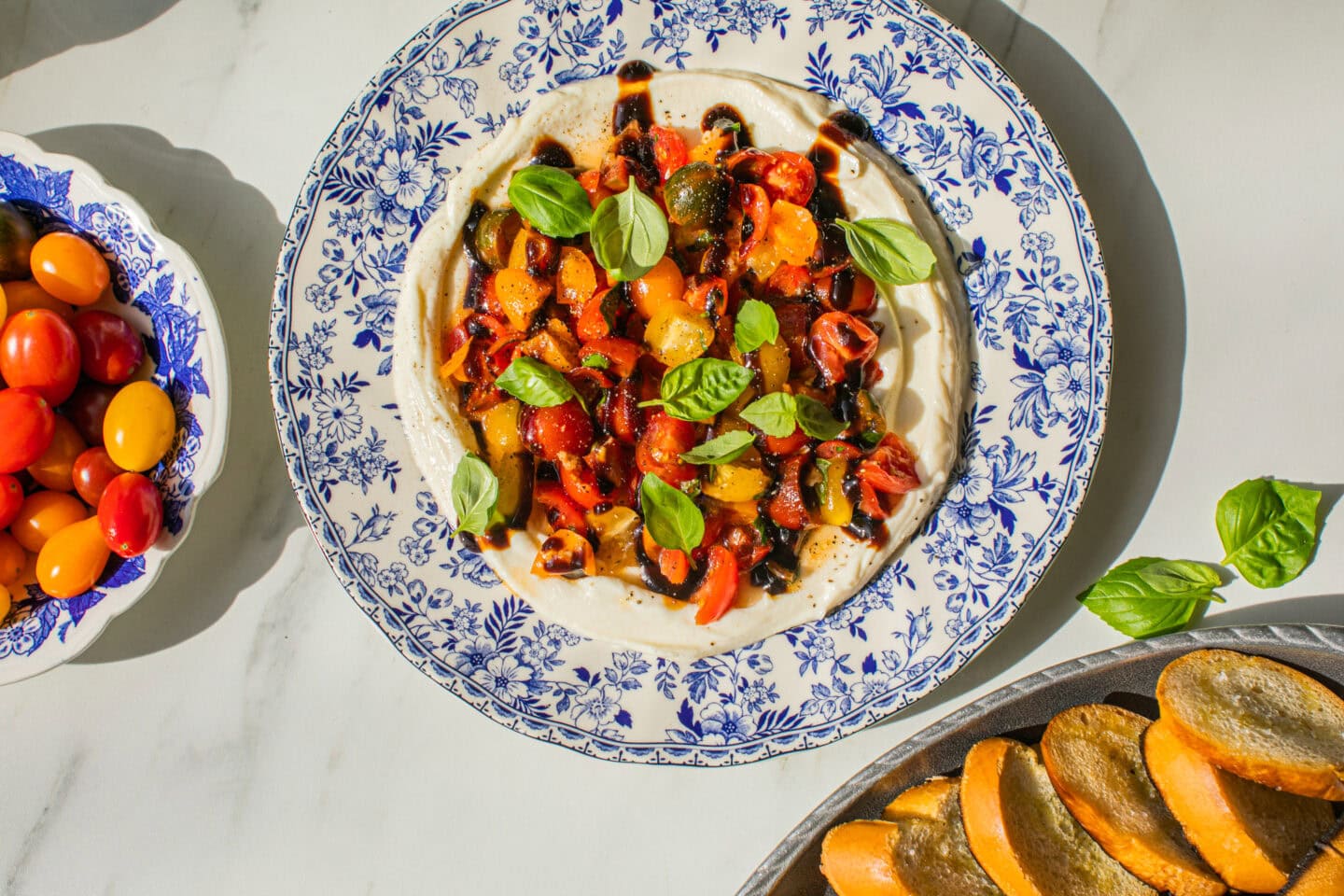 blue and white platter with whipped ricotta and bruschetta dip topper with tomatoes, basil and balsamic glaze