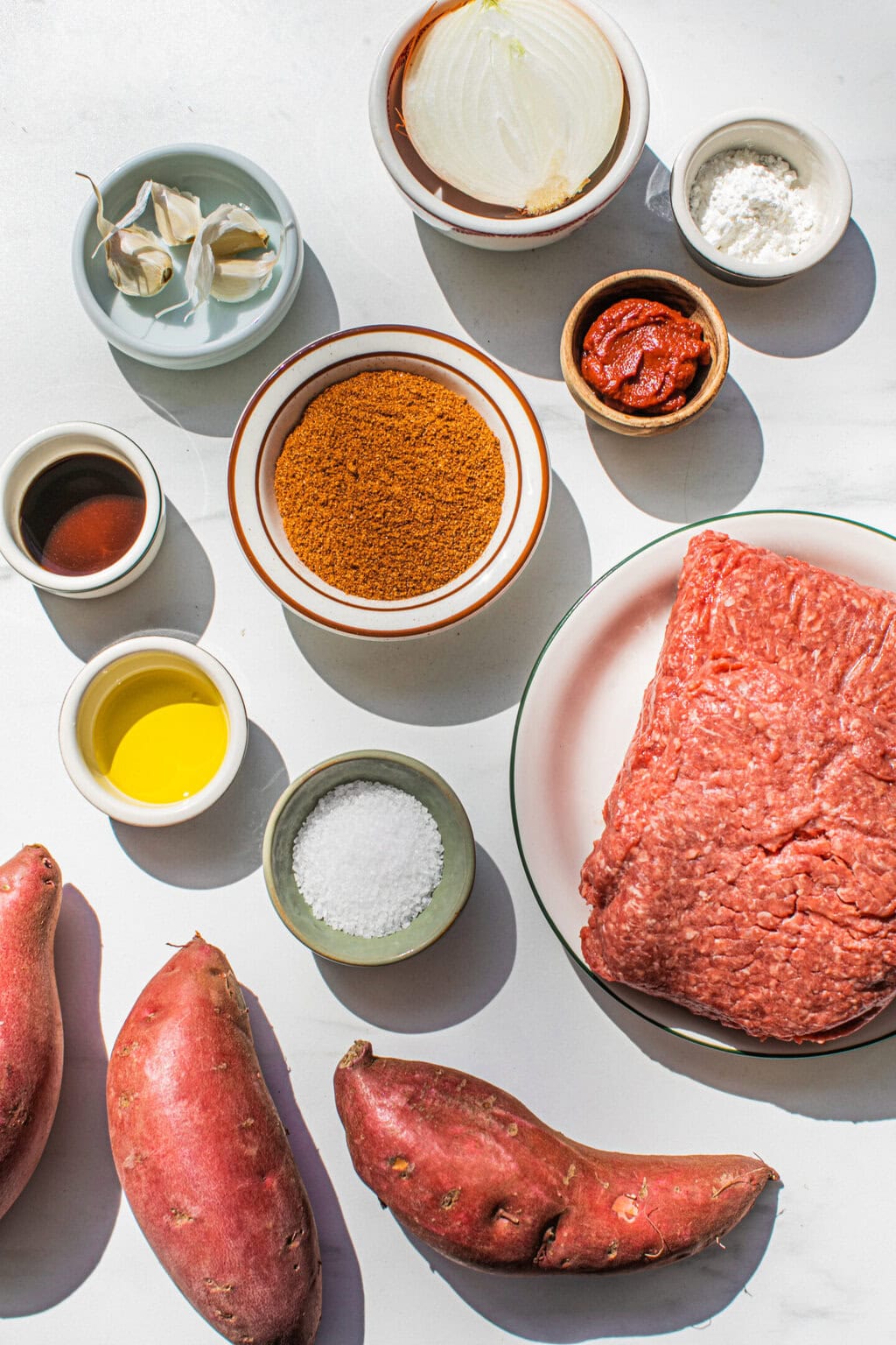 garlic cloves, onion, corn starch, tomato paste, taco seasoning, worcestershire sauce, olive oil, salt, ground beef and whole sweet potatoes