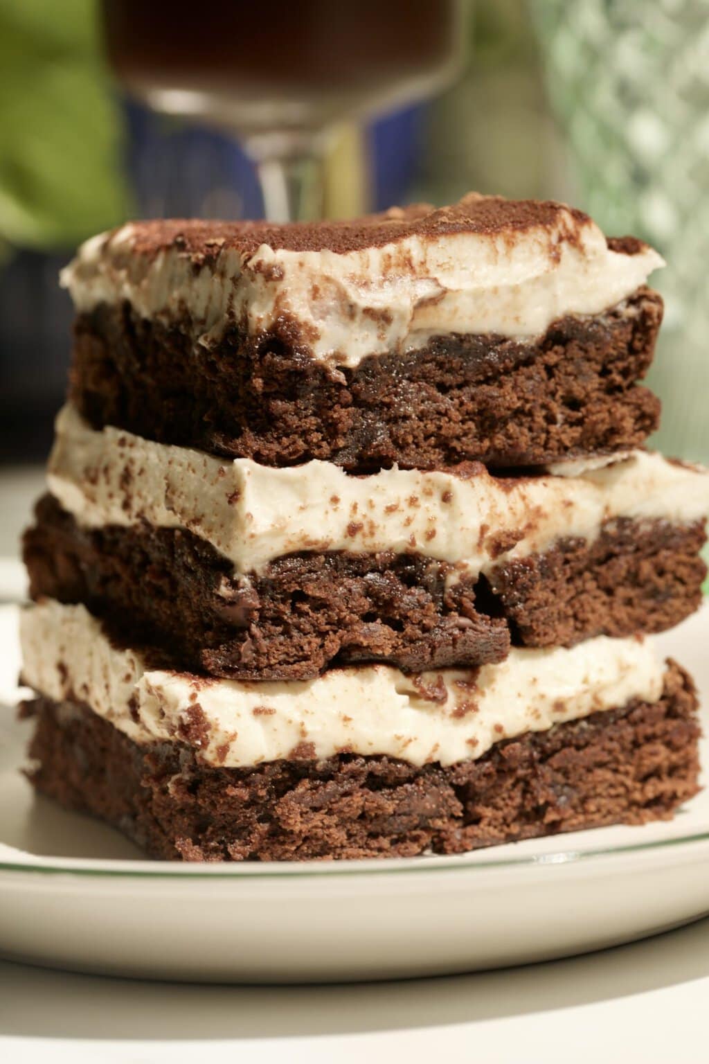 three brownie tiramisu slices on a plate with an espresso martini in the background