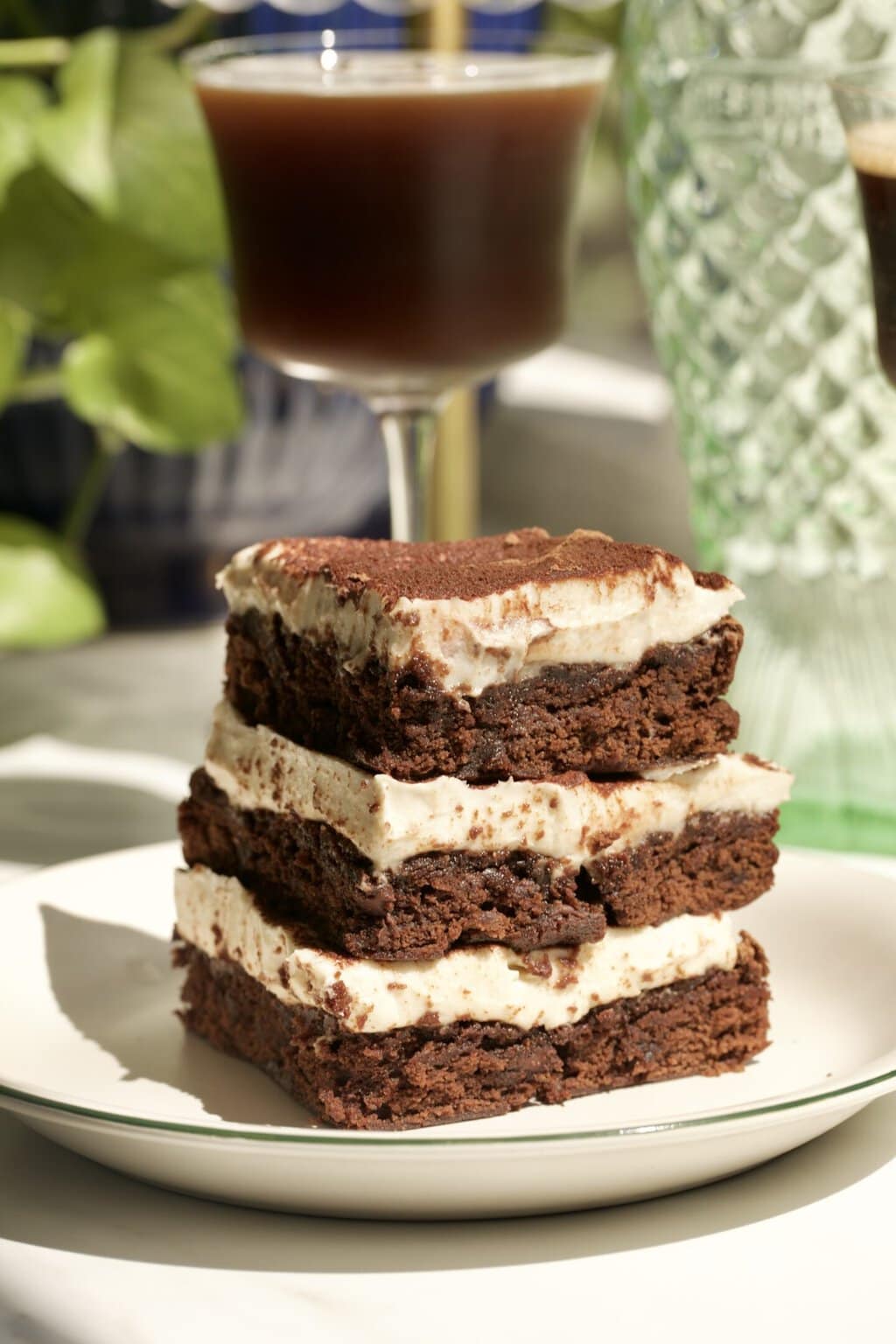 three brownie tiramisu slices on a plate with an espresso martini in the background