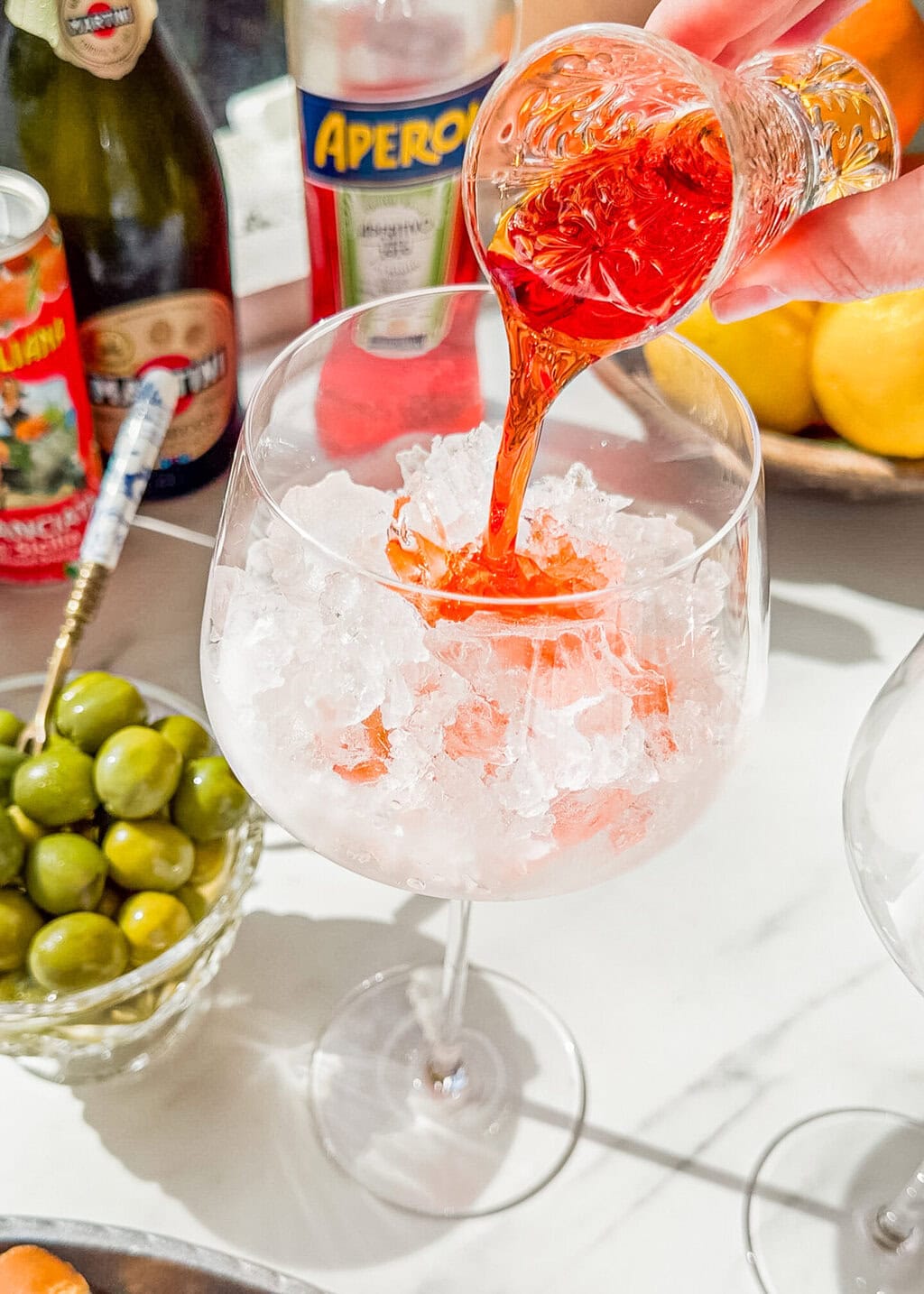aperol being poured into a wine glass with ice