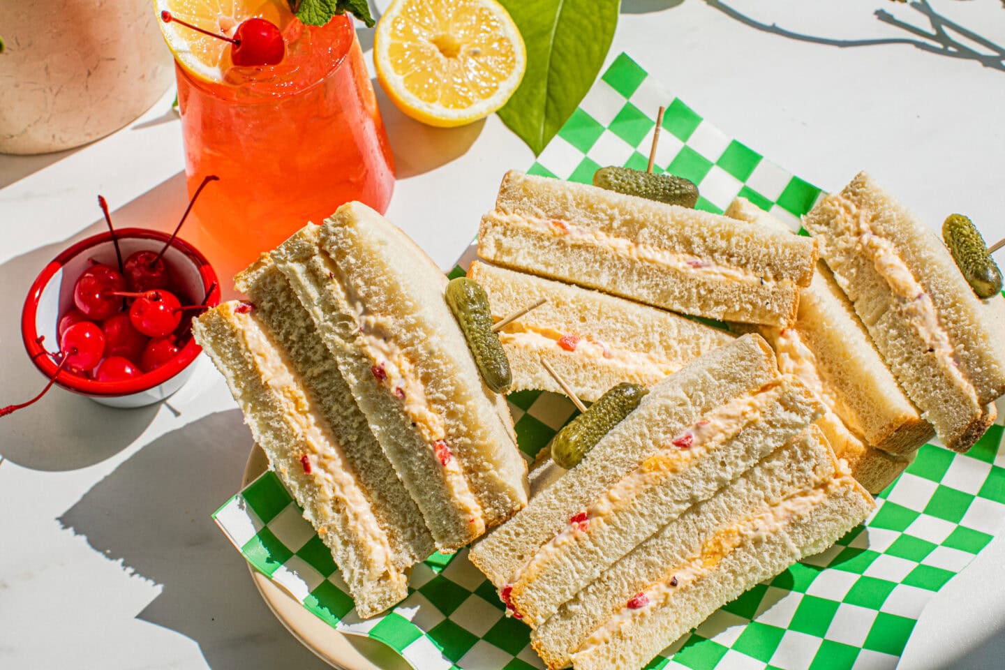 a platter of pimento cheese sandwiches on a green and white checkered platter